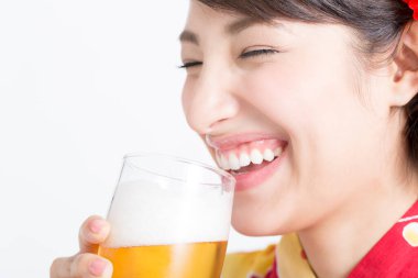 Geleneksel Japon kıyafetleri içinde bir kupa birayla genç bir Asyalı kadın.