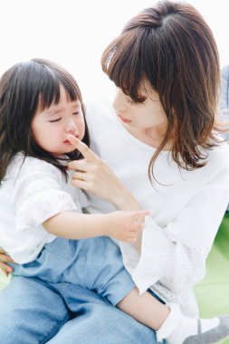 Asyalı anne ve kızı evde ağlıyorlar. 