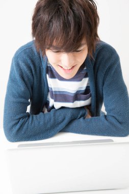 Masada bilgisayar kullanan genç Asyalı adam. 