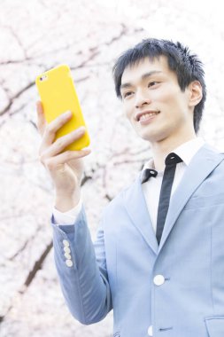 Parkta akıllı telefon tutan bir iş adamı