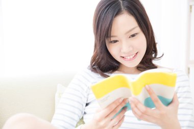 Evde kitap okuyan güzel Asyalı kadın