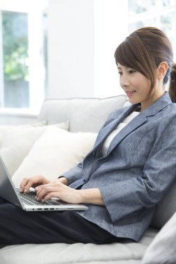 Modern ofiste dizüstü bilgisayar kullanan güzel bir Japon iş kadını.