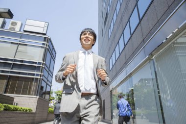 Sokakta koşan yakışıklı Asyalı iş adamının düşük açılı görüntüsü 