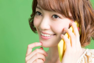 Güzel Japon kadının portresi yeşil arka planda akıllı telefondan konuşuyor. 
