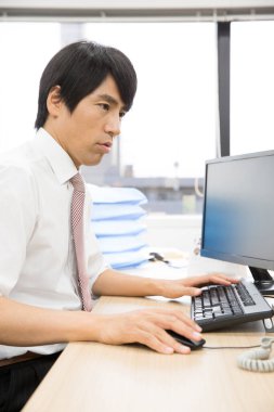 Asyalı işadamı ofiste bilgisayarla çalışıyor. 