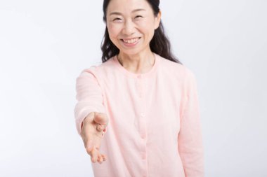 Tecrit edilmiş arka planda el sıkışmak için elini uzatan yaşlı Asyalı kadın. 