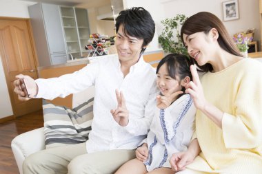 Aile oturma odasındaki kanepede selfie çekiyor.