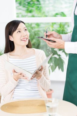 Güzel Asyalı kadın restoranda garsona sipariş veriyor.