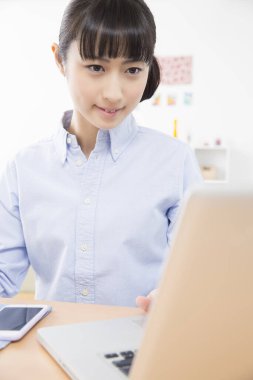 Genç Asyalı kız laptopla çalışıyor. 