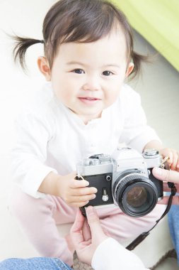 Gülümseyen çocuk elinde klasik bir kamera tutuyor.