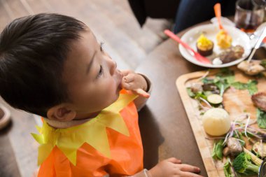 Genç çocuk festival masasında yemek yiyor.