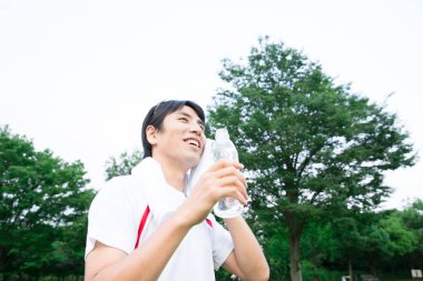 Yürüyüşten sonra su içen genç bir adamın portresi