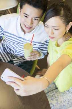 Asyalı çift kahve molasında selfie çekiyor. 