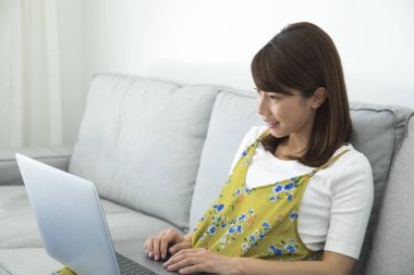 kadınla evde kanepenin üstünde laptop.