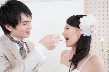 Güzel gelini düğün pastasıyla besleyen yakışıklı genç damat.      