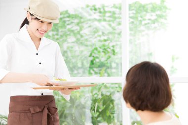 Ziyaretçilere yemek servisi yapan Asyalı garson. 