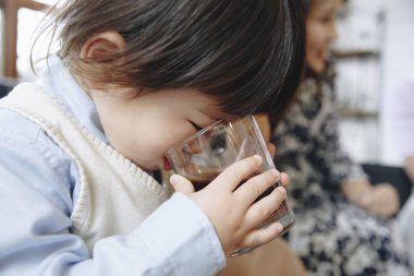 Asyalı kız evde su içiyor. 