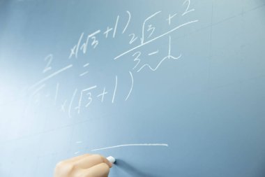 Tahtaya matematik yazan bir kadın eli
