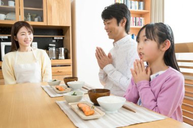 Mutlu Asyalı bir aile mutfakta kahvaltı yapıyor.