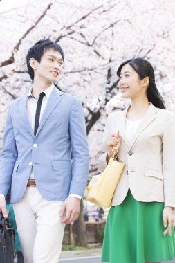 Parkta çiçek açan sakura ağaçları olan genç Asyalı çift.