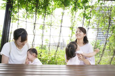 Parktaki küçük kızları olan Asyalı anneler.