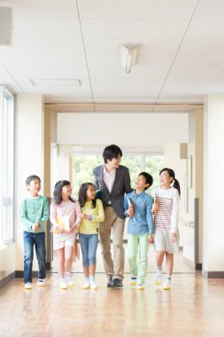 Öğretmenli bir grup Japon çocuk okul koridorunda yürüyor. 