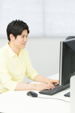 Ofiste bilgisayar kullanan Asyalı adam.