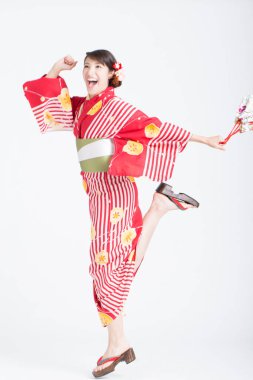 Beyaz stüdyo arka planında koşan geleneksel Japon kimonosu giyen Asyalı kadın.