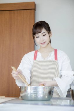 Güzel Japon kadın mutfakta yemek pişiriyor.