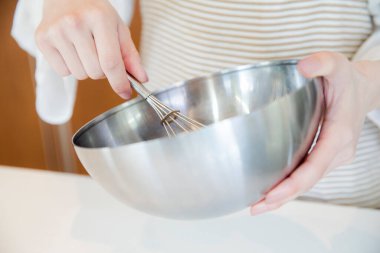 Bir kadın eli, çırpı ve kase tutarken yakınlaş. 