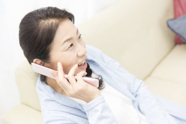 Evde cep telefonu kullanan Asyalı kadın.