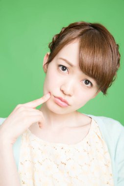 Yeşil arka planı düşünen genç bir kadın.