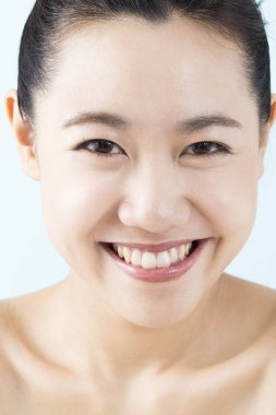 Mavi arka planda gülümseyen Asyalı kadın portresi