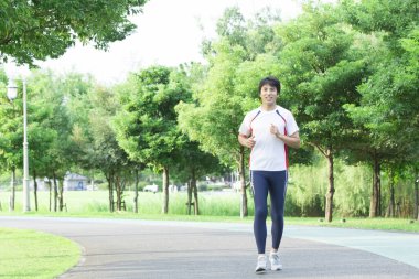 Genç yakışıklı Asyalı adam parkta koşuyor. 