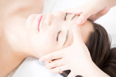 Genç ve güzel Japon kadın spa merkezinde yüz masajından zevk alıyor..