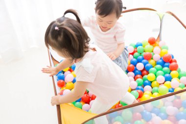 Sevimli küçük Japon kızları renkli toplarla oynuyorlar.