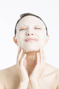 Beyaz arka planda maske takan güzel bir Asyalı kadın. Cilt bakımı kavramı