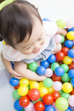 Mutlu küçük Japon kız renkli toplarla oynuyor.