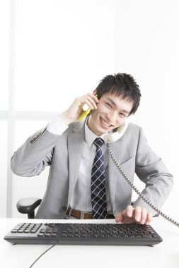 Ofiste telefonla konuşan genç Japon iş adamının yakın plan portresi.