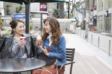 Genç kızlar kahve içip sohbet ediyorlar.