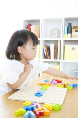 Küçük çocuk anaokulunda renkli plastik harflerle oynuyor..