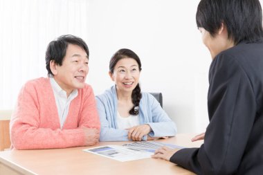 Üst düzey Asyalı çift bir emlakçıyla daire almayı tartışıyor.