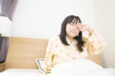 Yatakta pijamalı Asyalı kız. 