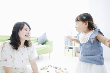 Evdeki oturma odasında annesiyle oynayan tatlı Asyalı küçük kız.