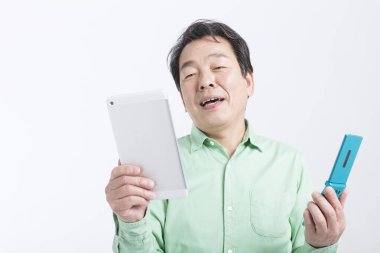 Beyaz arka planda tablet bilgisayarı ve cep telefonu olan Asyalı iş adamı.