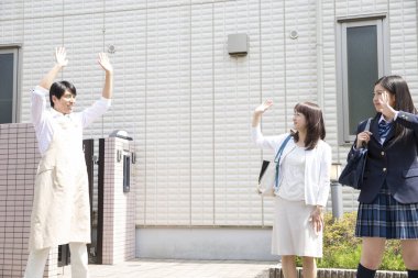 Asyalı bir adam karısına ve kızına veda ediyor.