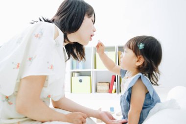 Evdeki oturma odasında annesiyle oynayan tatlı Asyalı küçük kız.