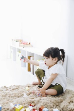 Tatlı Asyalı kız oturma odasında yerde oynuyor.