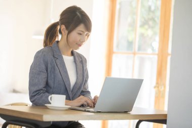 Dizüstü bilgisayarla çalışan Asyalı genç kadın.