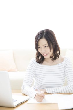 Genç Asyalı öğrenci evde dizüstü bilgisayarla çalışıyor.